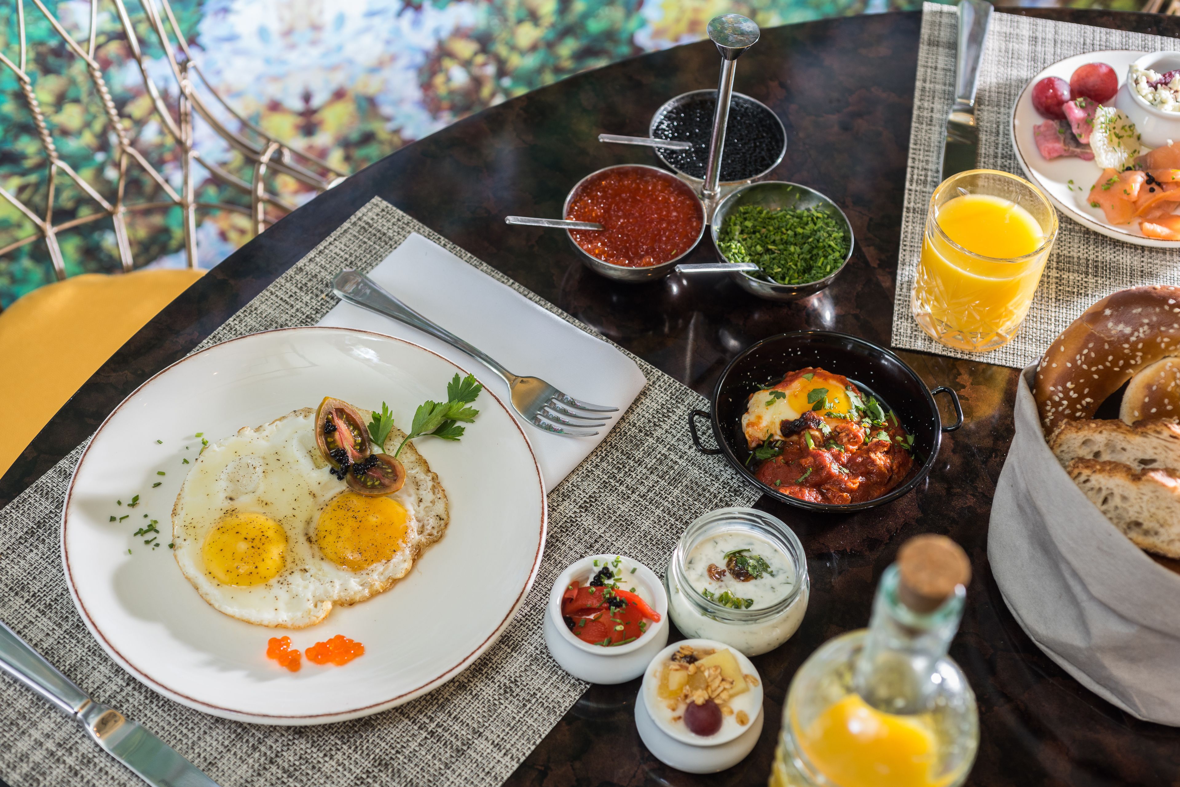 A breakfast table with various dishes including eggs, sauces, and a glass of orange juice.