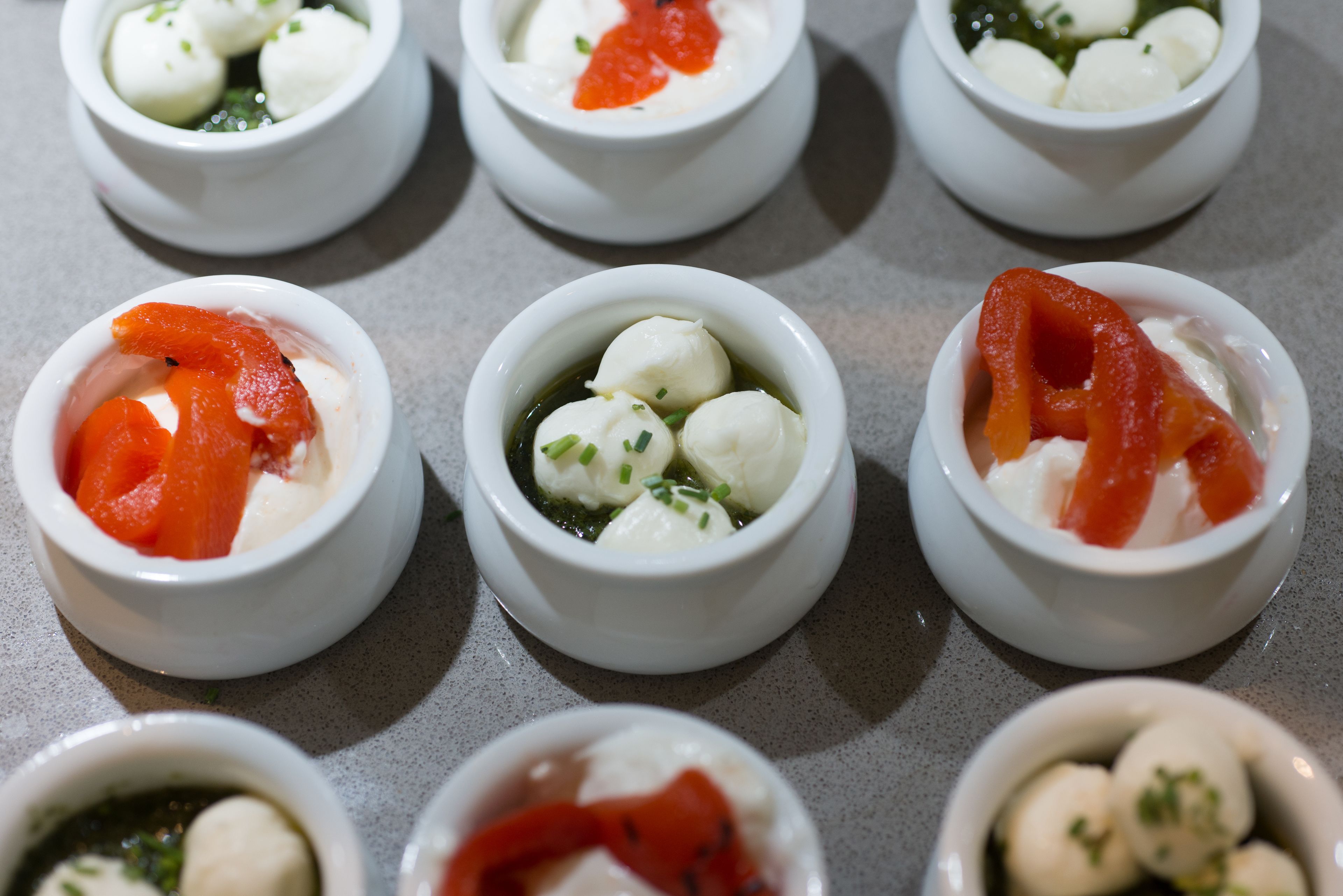 A tray of small bowls containing various food items, likely appetizers or snacks.