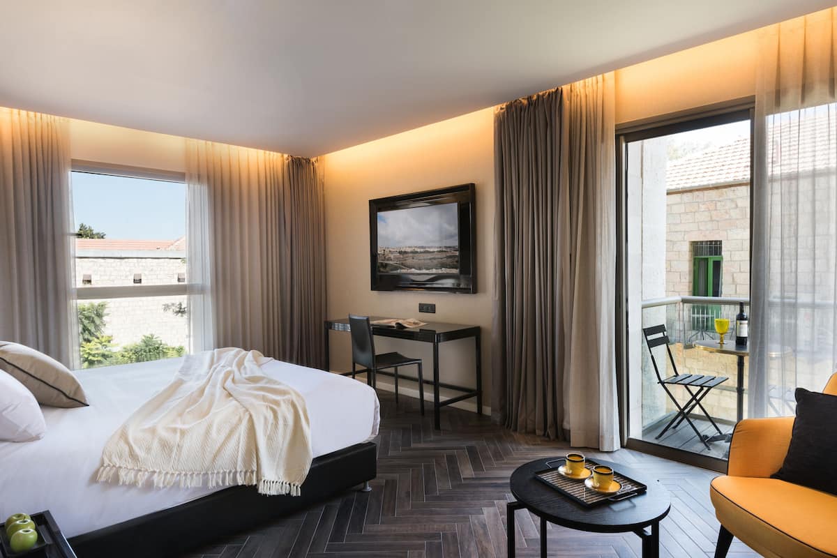 Ein Hotelzimmer mit Bett, Schreibtisch, Stuhl, Balkon und einem Tisch mit Tablett.