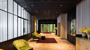 Un vestíbulo moderno con suelo de estampado geométrico, un sillón verde, un sillón amarillo y una alfombra roja.