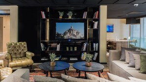 Un área de estar moderna con un televisor de pantalla plana grande, un sillón de cuero, sofás y una mesa de centro.
