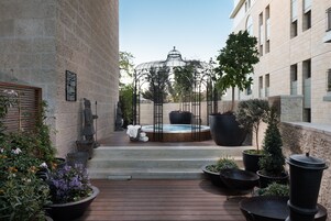 Un patio con un jacuzzi, plantas en macetas y un pabellón.