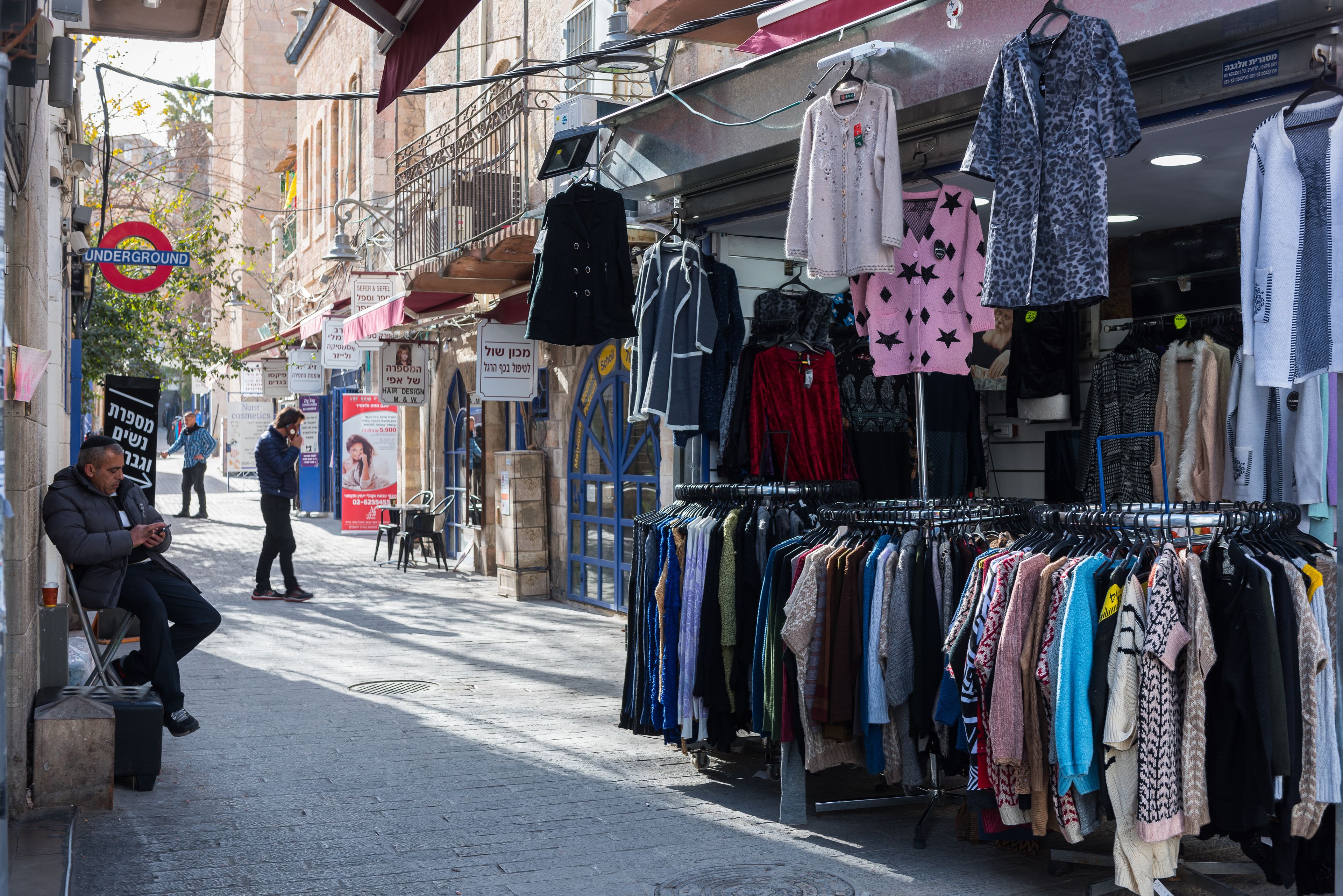 A street with a clothing store displaying various garments.