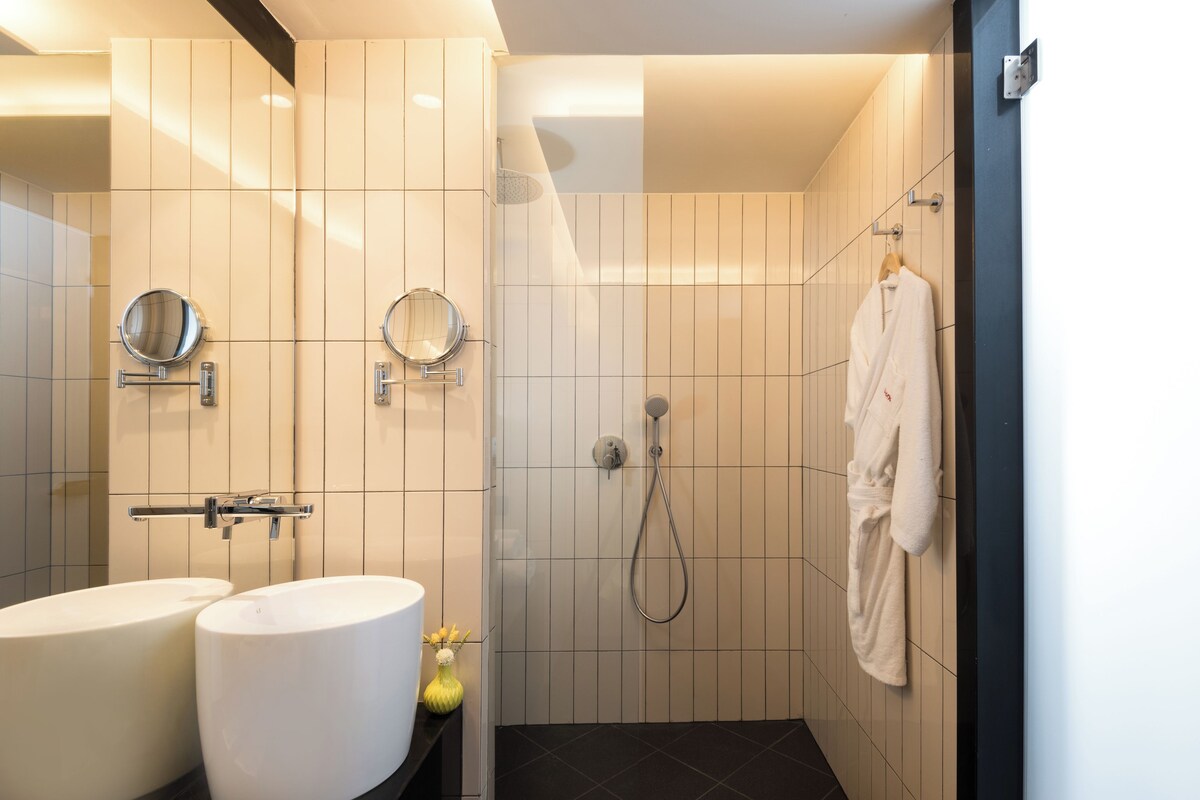 Un baño moderno con dos lavamanos, una ducha y un perchero para toallas.