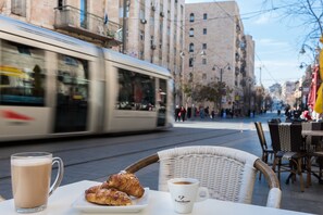 A table with a mug, a plate with pastries, and a wicker chair. - Leonardo Boutique Jerusalem (Jerusalem)