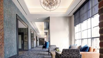 A hotel lobby with a patterned carpet, a chandelier, and a seating area with patterned chairs and a sofa.