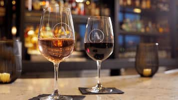 Two wine glasses on a bar counter with a blurred background of shelves and bottles.