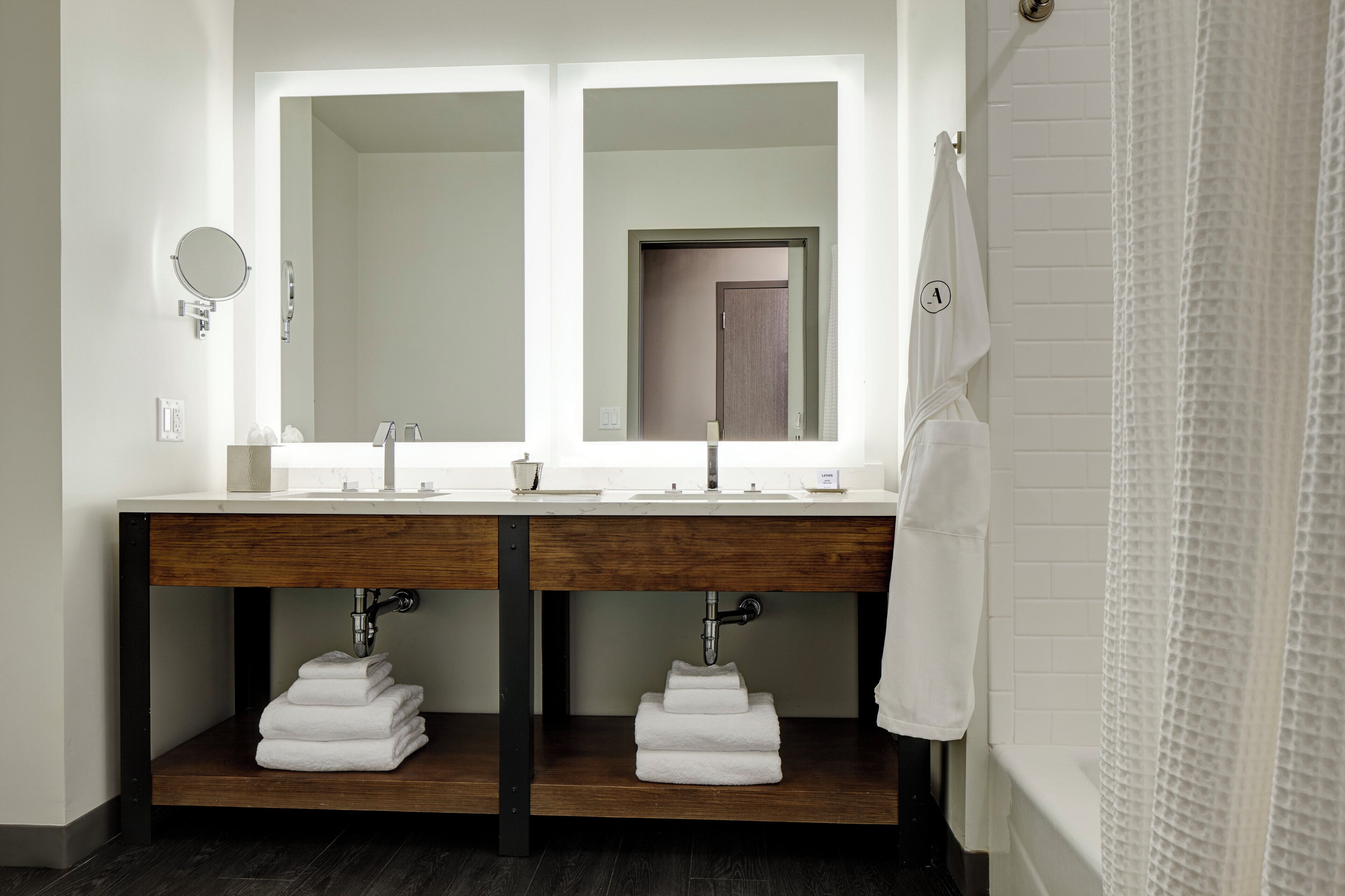 Une salle de bain moderne avec un double vasque, un grand miroir et un porte-serviettes.