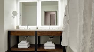 Une salle de bain moderne avec un double vasque, un grand miroir et un porte-serviettes.