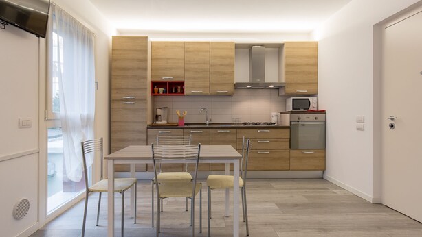 Une cuisine moderne avec des meubles en bois, une table à manger avec des chaises et un four à micro-ondes encastré.