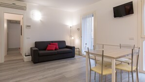 Un salon moderne avec un canapé, une table à manger et un téléviseur fixé au mur.