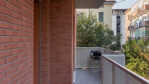 Un balcon avec une balustrade en métal, une chaise et une petite table.