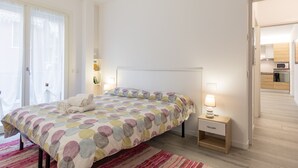 Une chambre à coucher avec un lit, une table de chevet et une vue sur la cuisine.
