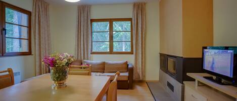 Una sala acogedora con una mesa de comedor de madera, un sofá, un televisor y una chimenea.