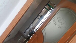 A wooden door with a glass panel, a metal handle, and a decorative floral arrangement. - Hotel Mistef (Falerna)