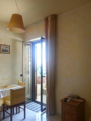 A room with a dining table, chairs, a cabinet, and a sliding glass door leading to an outdoor area. - Hotel Mistef (Falerna)