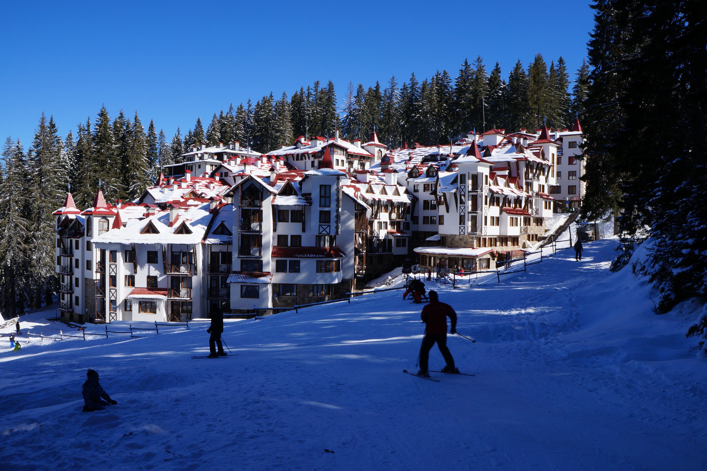 Ein Skigebiet mit mehrstöckigen Gebäuden, Skipisten und schneebedeckten Bäumen.