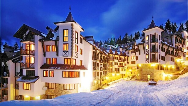 A snow-covered ski resort with multi-story buildings featuring balconies and ski lifts. - Apart Hotel The Castle (Smolyan)