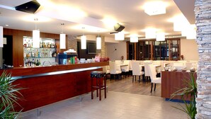 Un área de bar moderna con un mostrador de madera, varias lámparas colgantes y una variedad de botellas y vasos.