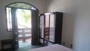 Une chambre à coucher comprenant un lit, une armoire et une porte donnant sur un balcon.