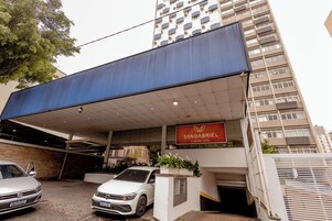 Ingresso di un hotel con area parcheggio coperta, due auto parcheggiate e un cartello con la scritta 'Sangabriel A Nearby Hotel'.
