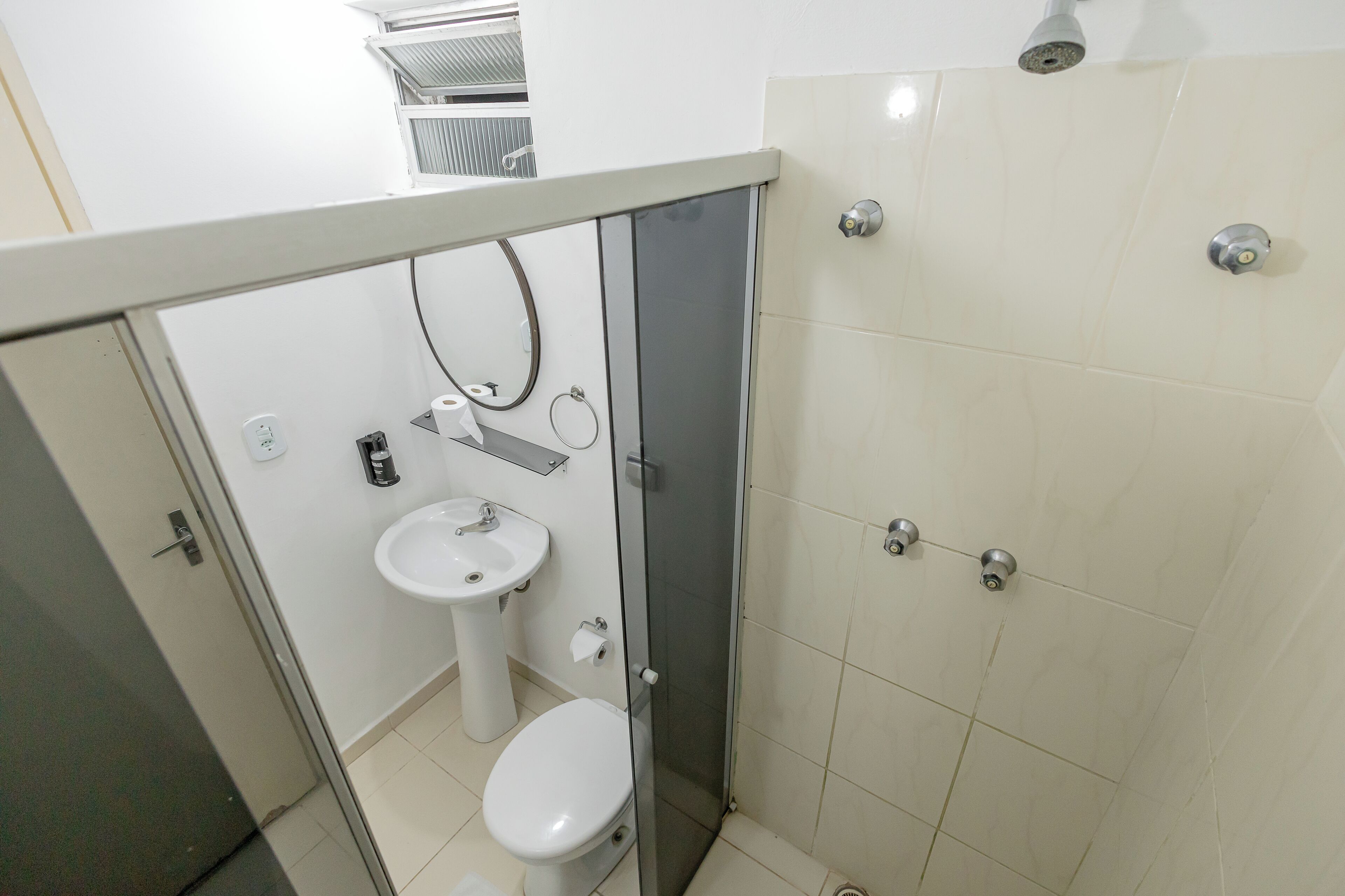 A small bathroom with a toilet, sink, and shower.