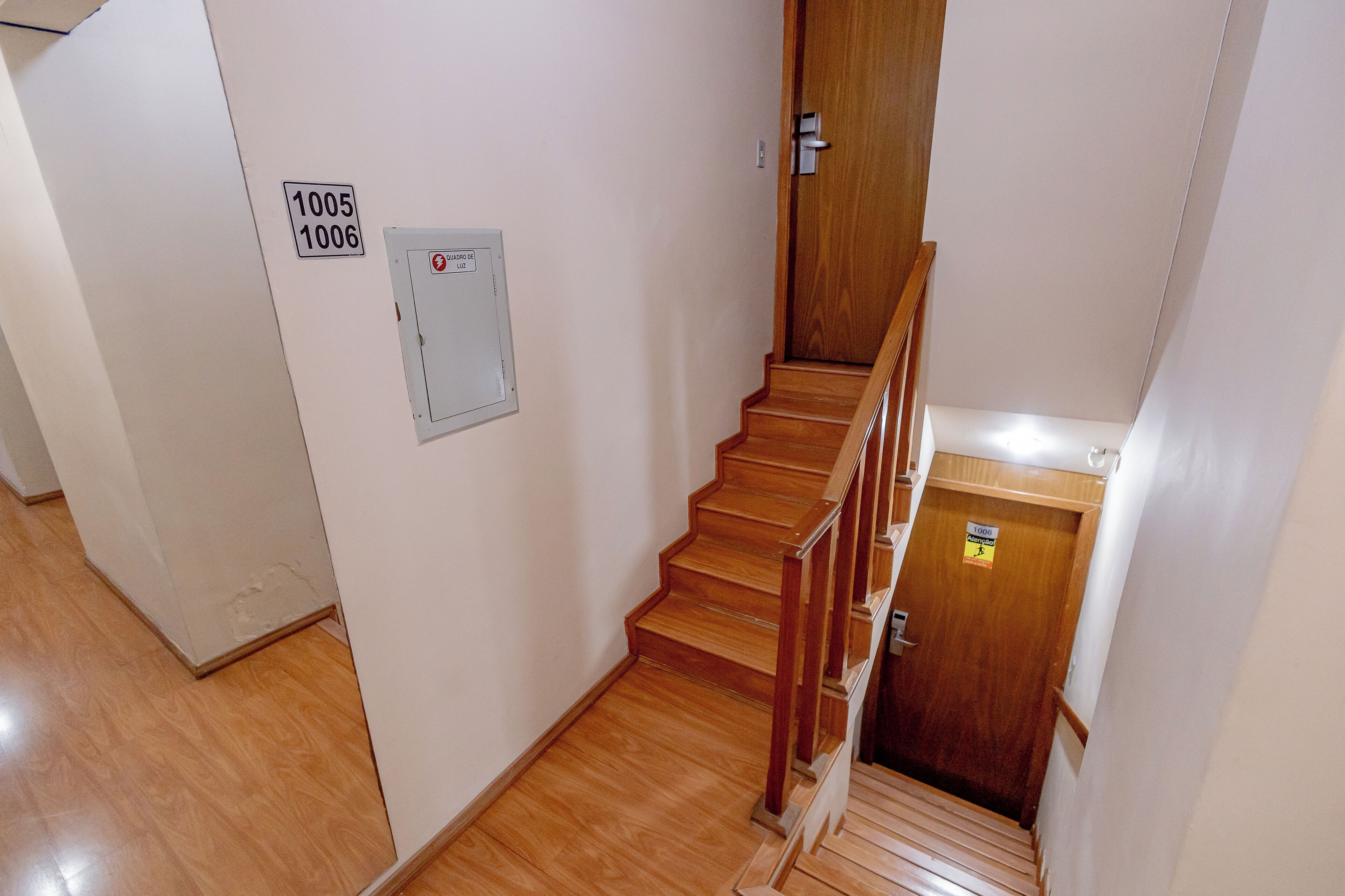 A staircase with wooden steps and a handrail, leading to a door marked with numbers 1005 and 1006.