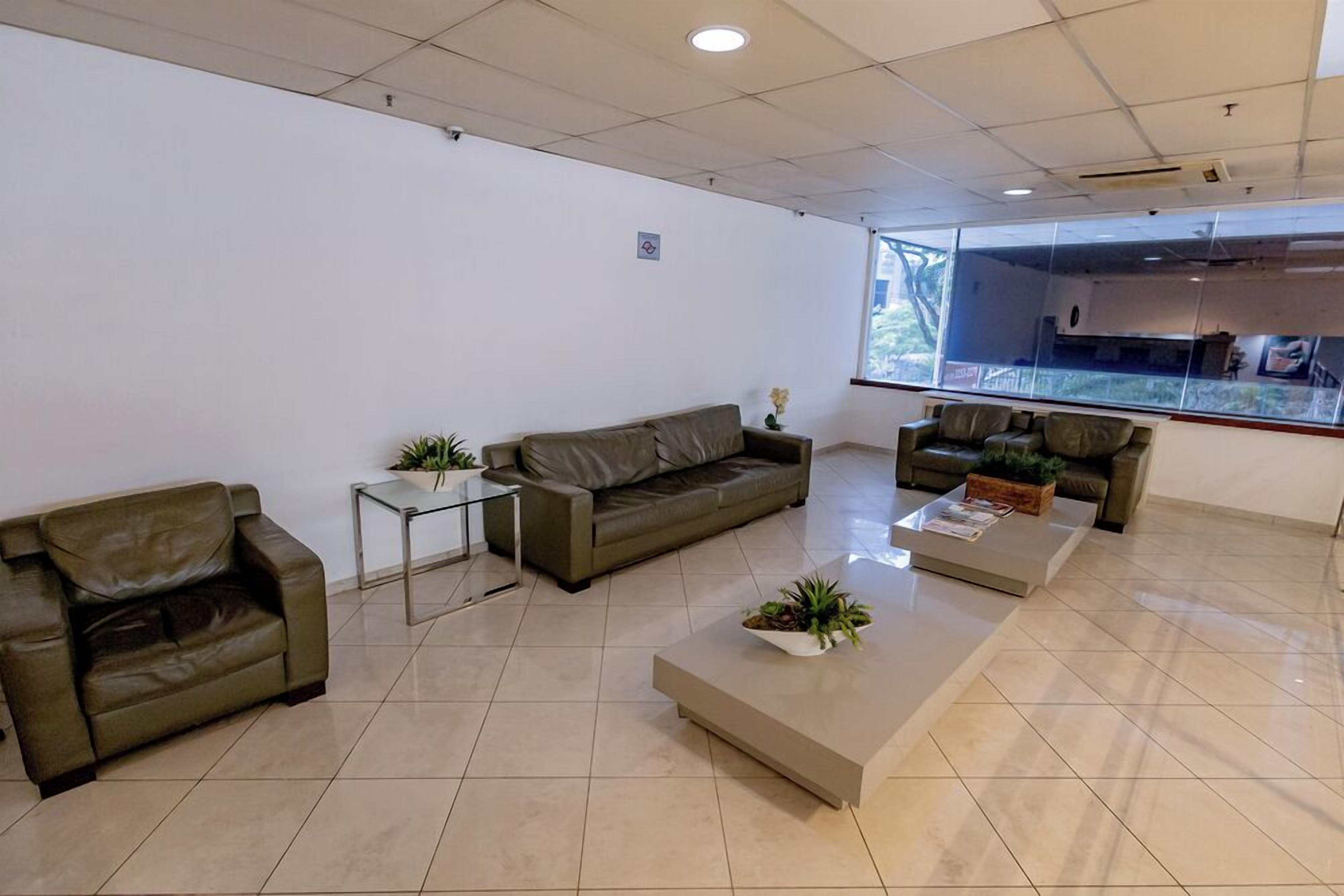 A spacious, modern waiting area with leather sofas, a coffee table, and potted plants.