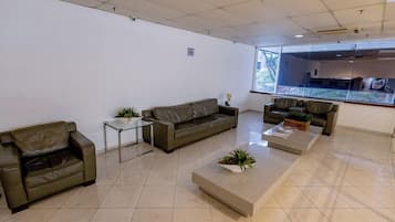 A spacious, modern waiting area with leather sofas, a coffee table, and potted plants.