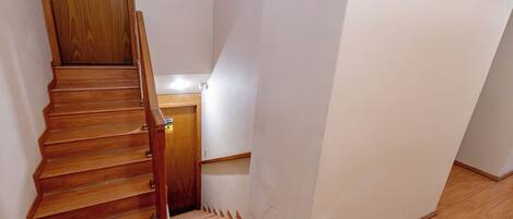 Eine Holztreppe führt zu einer Zwischenebene mit einem Holengeländer.