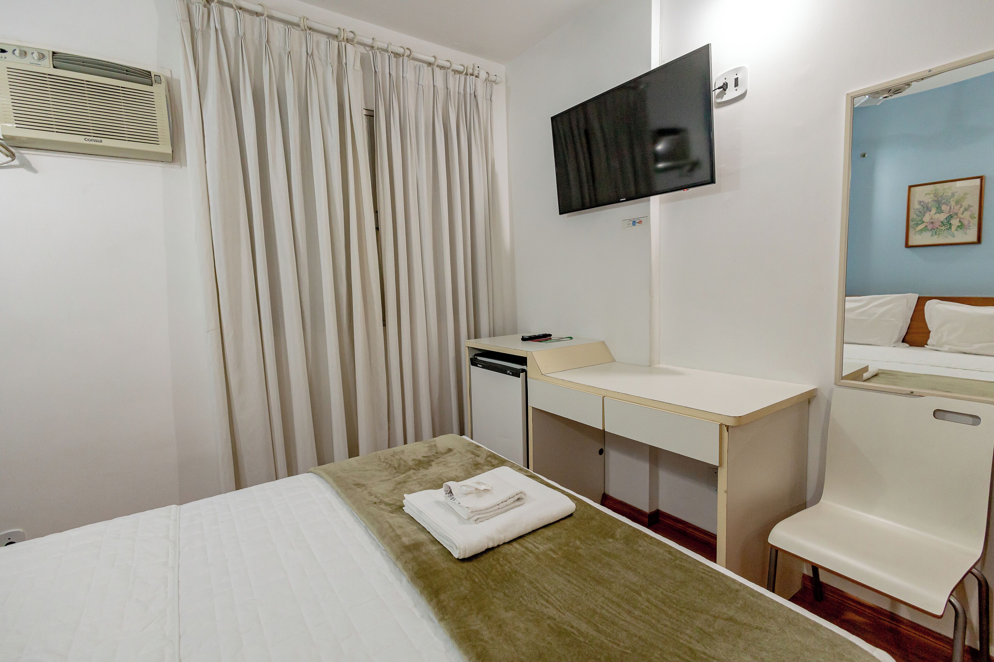 A hotel room with a bed, a desk, a television, and a bathroom.