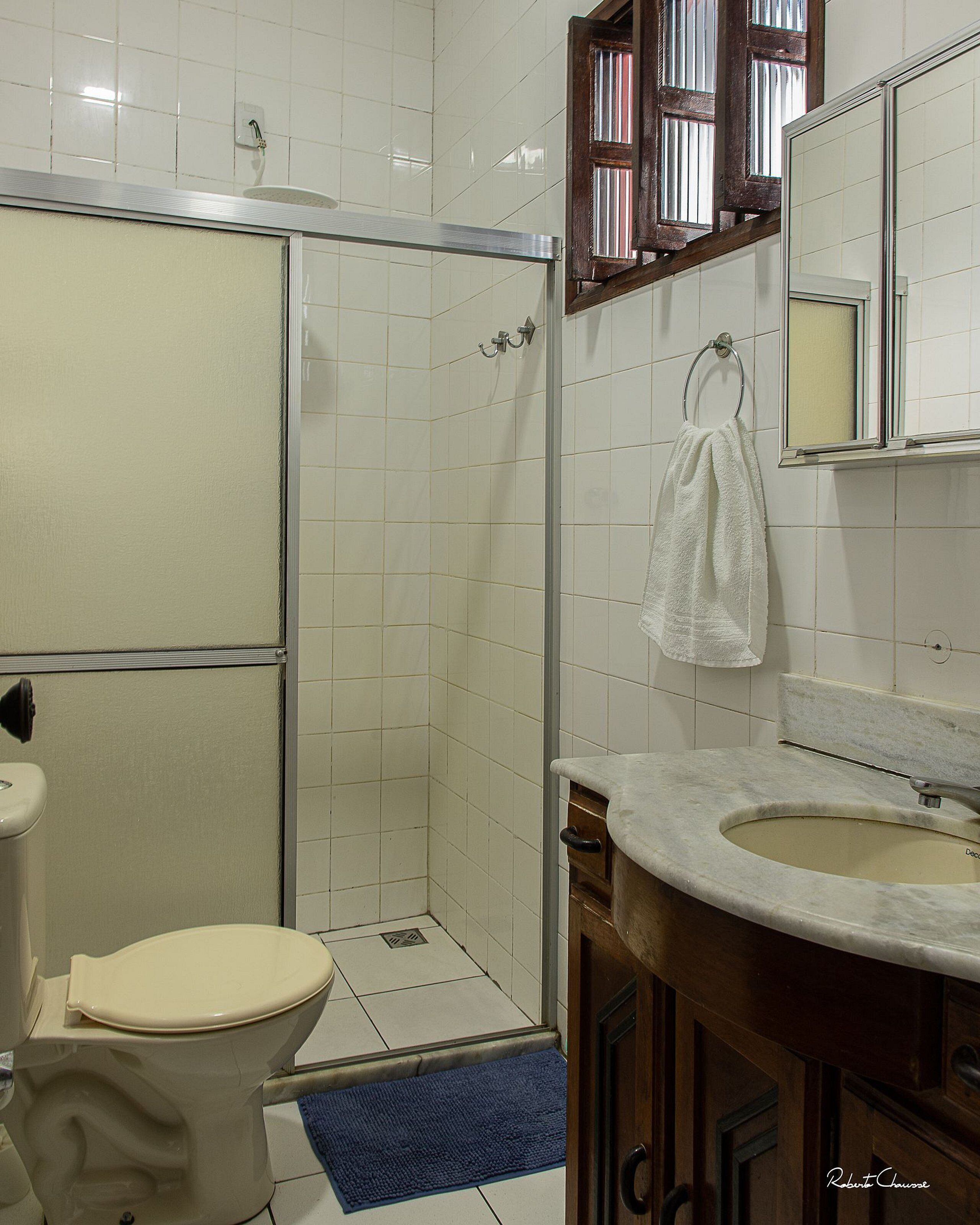 A bathroom with a toilet, shower, sink, and a towel hanging on the wall.