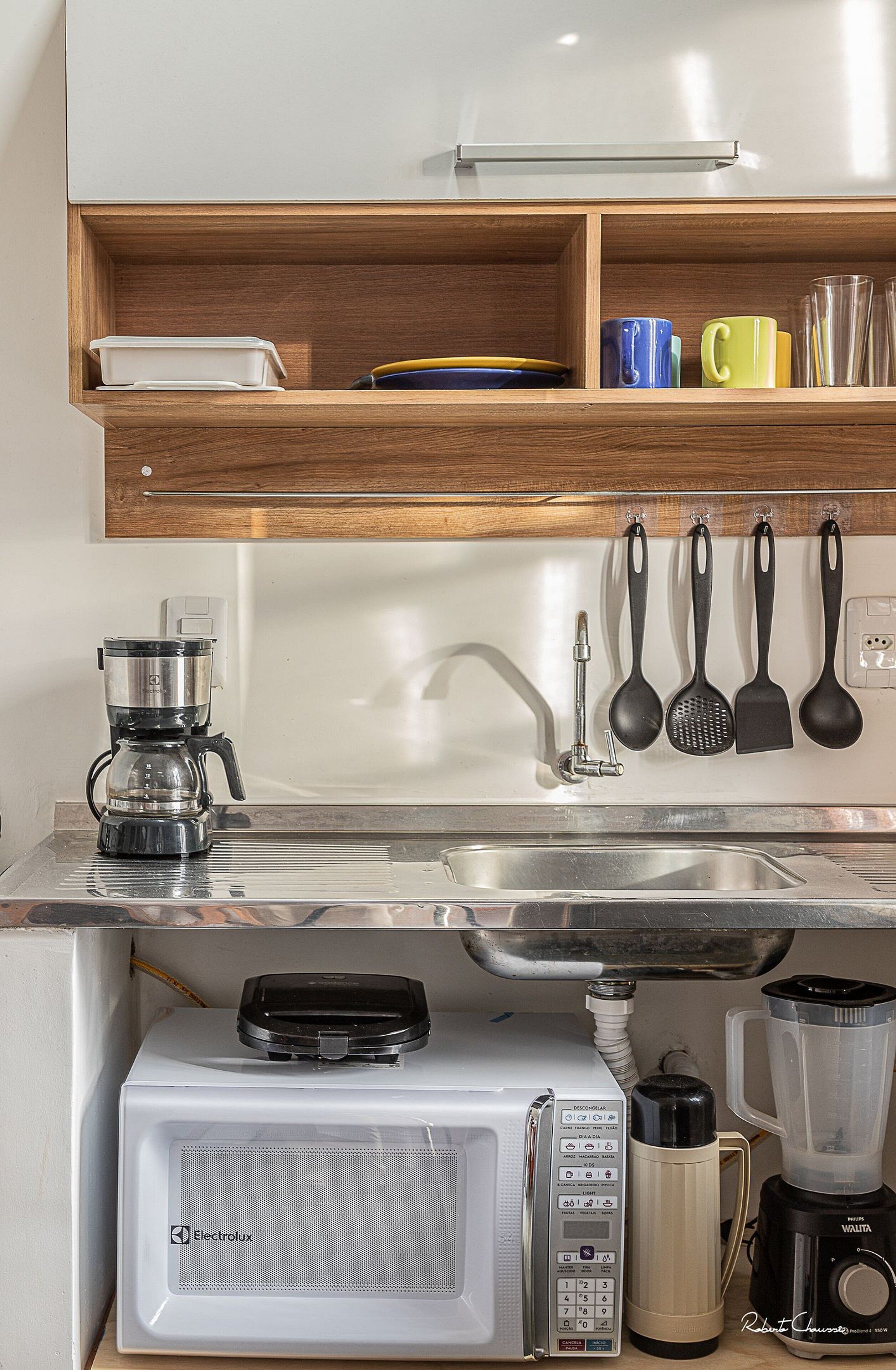 Cocina compacta equipada con microondas, cafetera y licuadora.