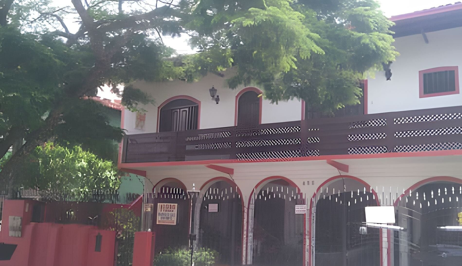 Um edifício de dois andares com varanda e janelas em arco.