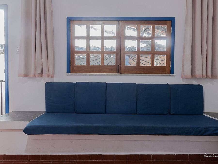 Un sofá azul frente a una pared blanca con una ventana arriba.