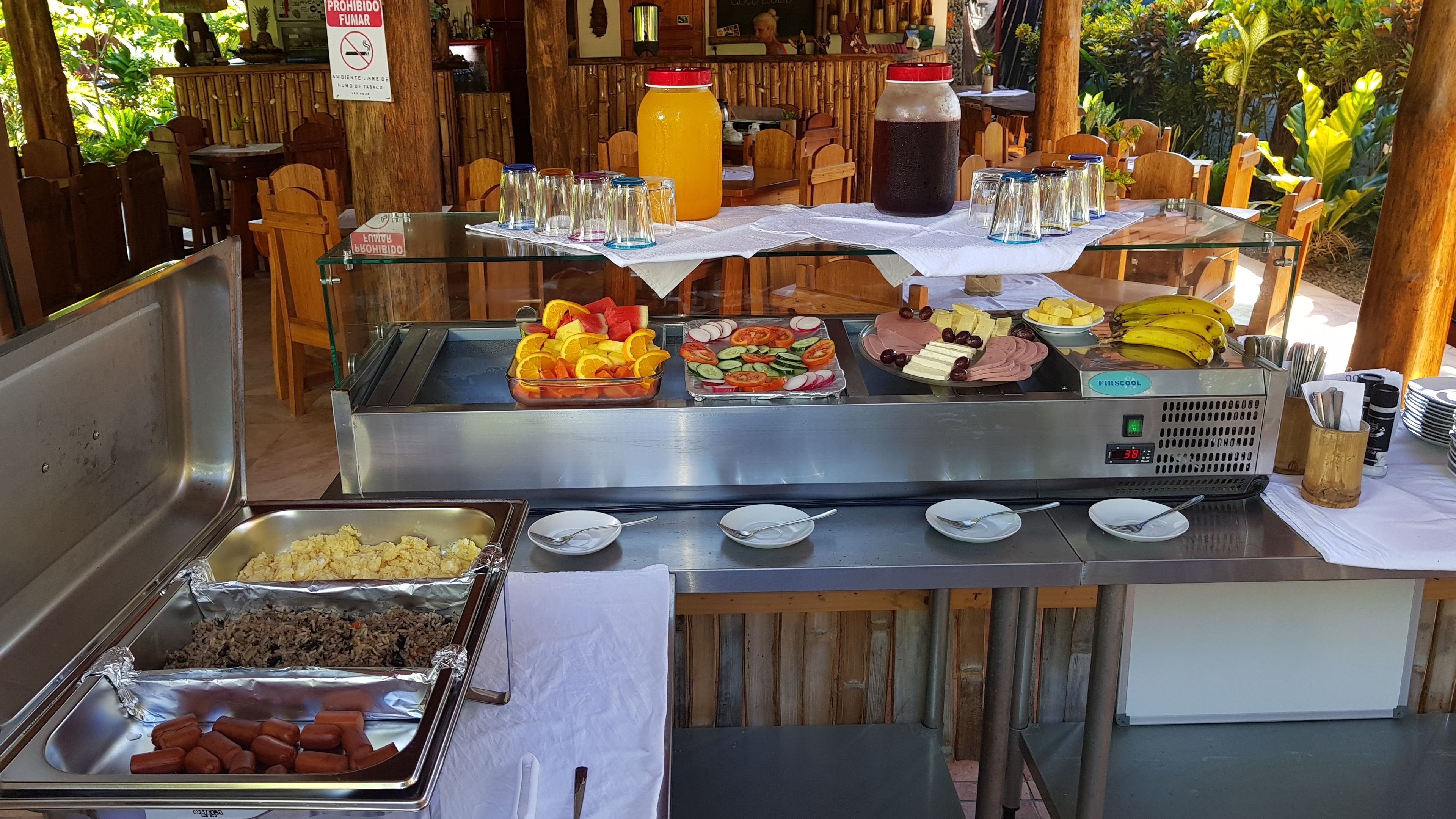 Un bufé con diferentes opciones de comida, incluyendo frutas, verduras y perritos calientes.