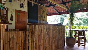 Un área de recepción con un mostrador de bambú, una puerta de madera y una planta en maceta.