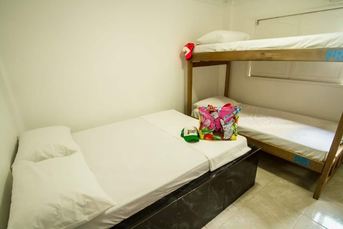 A bunk bed room with a small table and a colorful bag on the lower bunk.