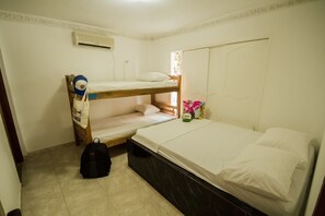 A dormitory room with bunk beds, a suitcase, and a box of tissues. - La Perla Hostel (Santa Marta)