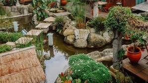 A traditional Japanese-style garden with a pond, potted plants, and wooden buildings with tiled roofs. - Vila Air Natural Resort (Lembang)