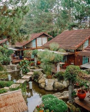 Ein traditioneller japanischer Garten mit Teich, Kübelpflanzen und Holzbauten mit Ziegeldächern.