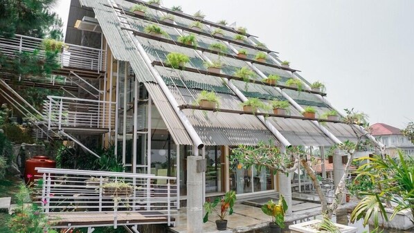 A modern building with a sloped roof covered in green plants, a staircase, and a small outdoor seating area.