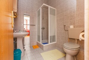 Kylpyhuoneessa on suihku, wc, pesuallas ja ovi, joka johtaa toiseen huoneeseen.