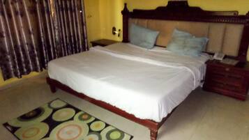 Un dormitorio con una cama, una mesita de noche, un cabecero de madera y una alfombra estampada.