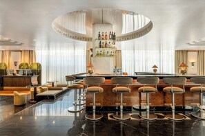 A bar area with a circular ceiling design, bar stools, and a bar counter. - The Dean Munich, Autograph Collection® (Munich)