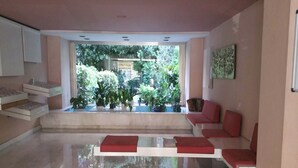 Una sala moderna con un conjunto de sofás, una mesa de centro y vistas al exterior con vegetación.