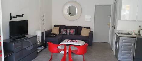 Una sala de estar con un sofá, un televisor de pantalla plana, una mesa de centro y una silla roja.