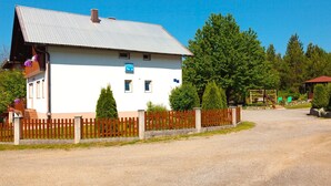 A white building with a metal roof, a wooden fence, and a clear blue sky. - House Zdravko (Plitvicka Jezera)