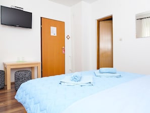 A hotel room with a bed, a desk, a television, and two doors. - House Zdravko (Plitvicka Jezera)