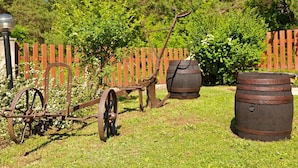 A rustic outdoor setting with a wooden fence, a metal cart, and two wooden barrels. - House Zdravko (Plitvicka Jezera)